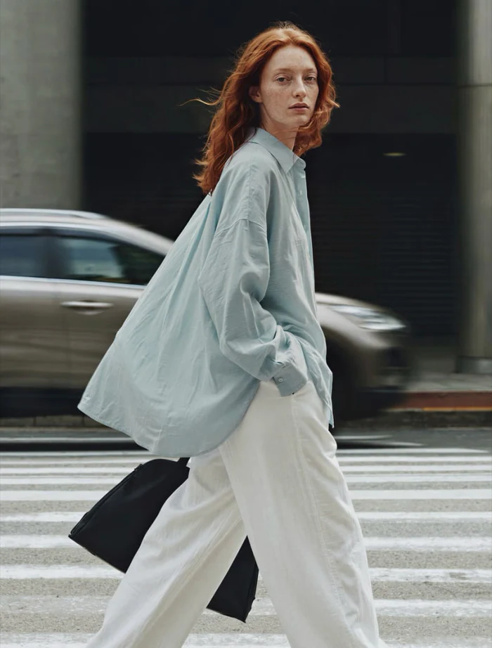 A model photographed mid-stride on a city crossing — pose set in motion