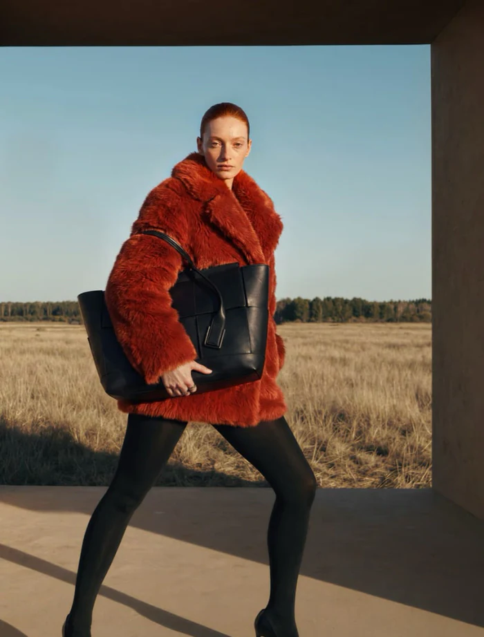 A red shearling coat photographed against an open field at golden hour
