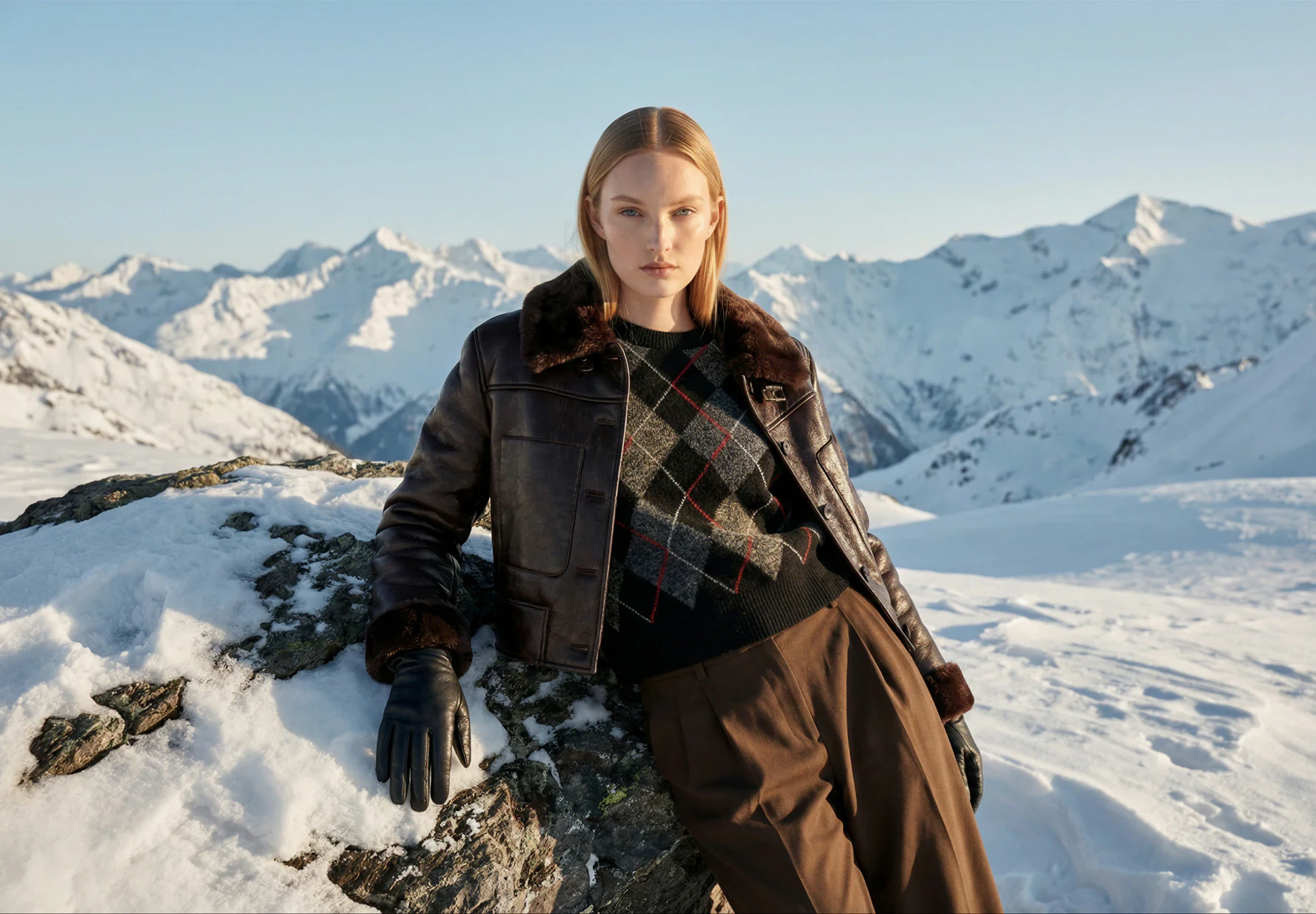 AI-generated on-model image: shearling coat and winter layers photographed on a snowy ridge, wide frame