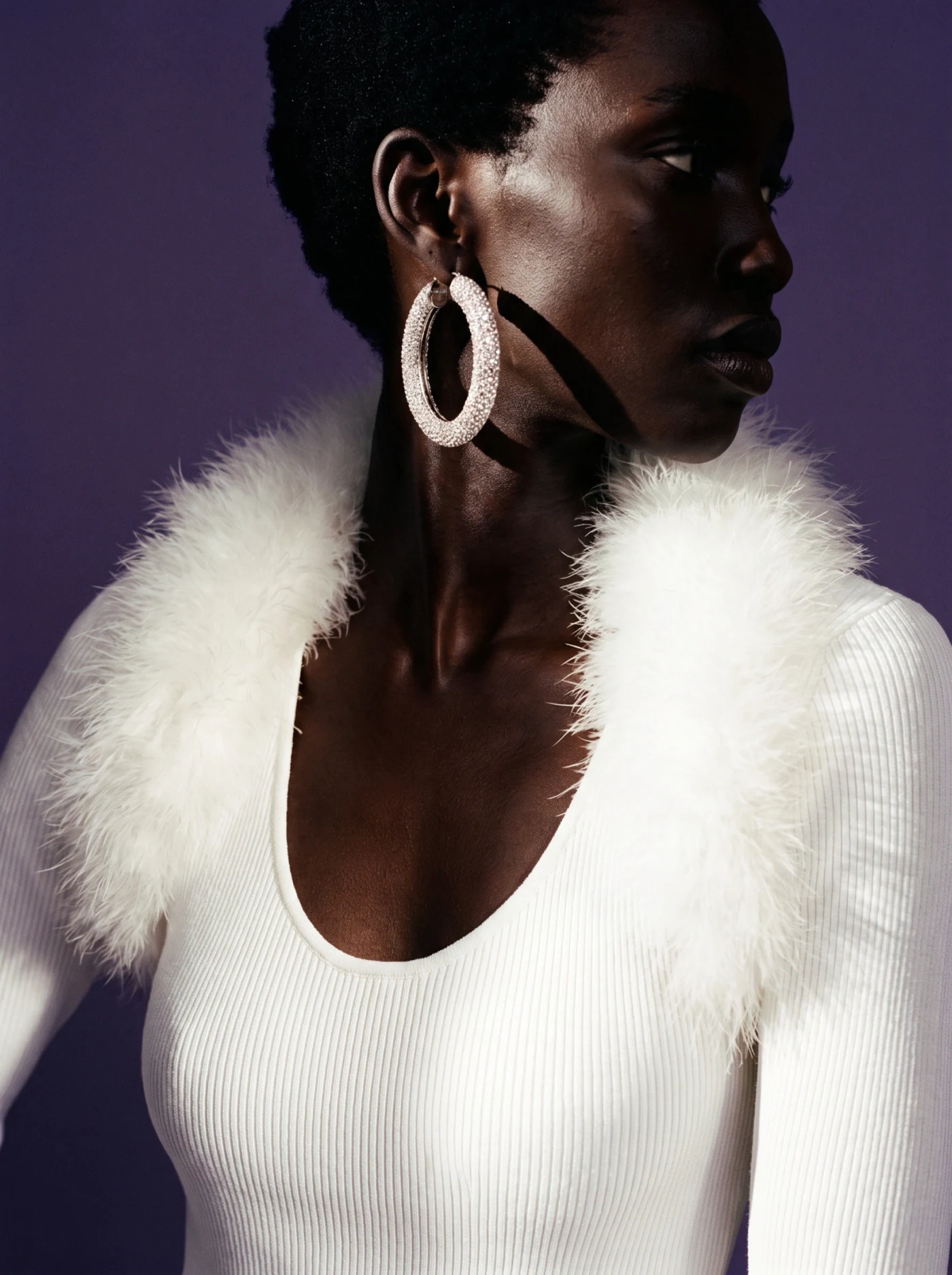 The same AI model in a white knit with a feather collar, studio lookbook shot