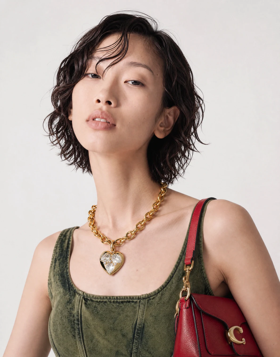 Photoreal AI fashion model in a washed denim corset with a gold chain necklace and red bag