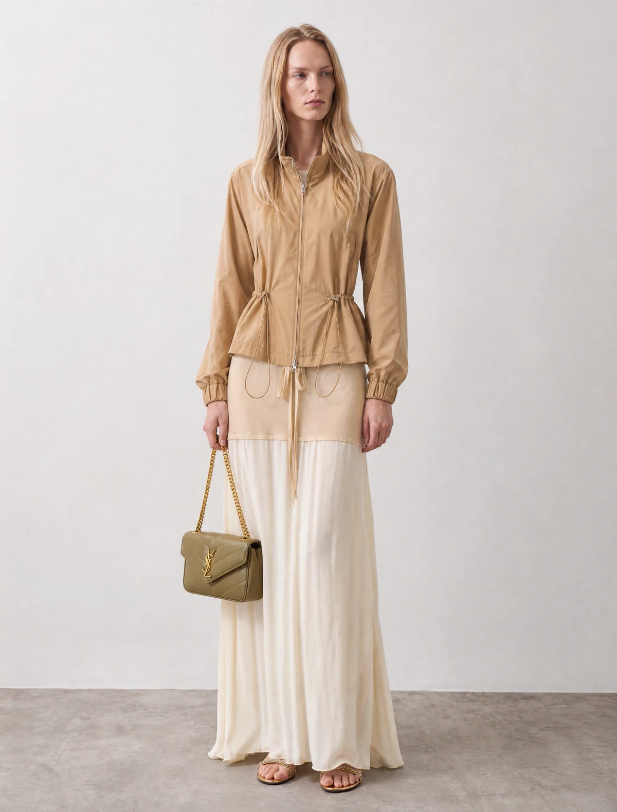 AI-generated on-model image: beige high-neck jacket over a pleated maxi skirt