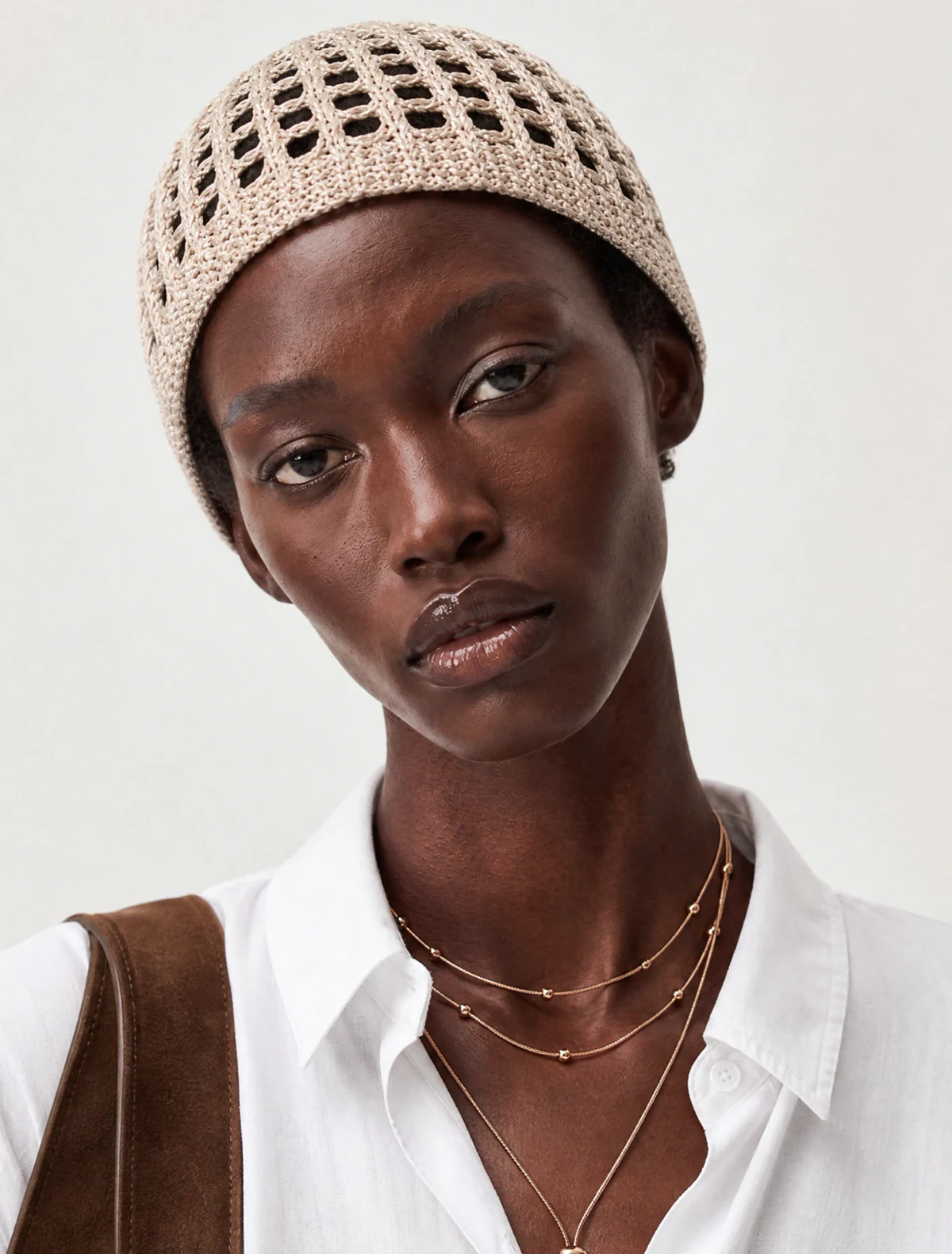 AI-generated on-model image: white linen shirt with a crochet hat and a suede tote, close-up portrait