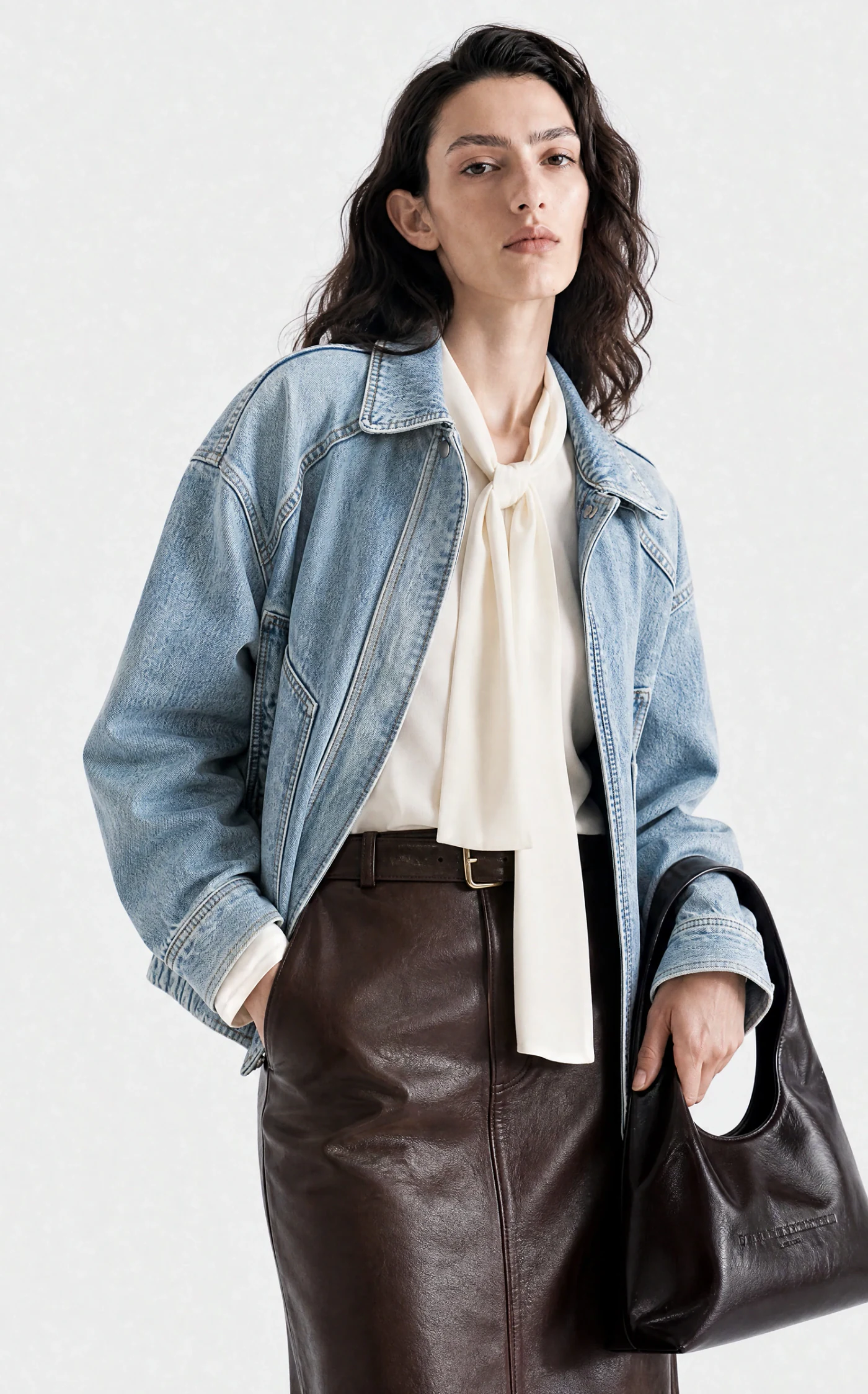 Vestira PDP image — light-wash denim jacket with a brown leather skirt, front view