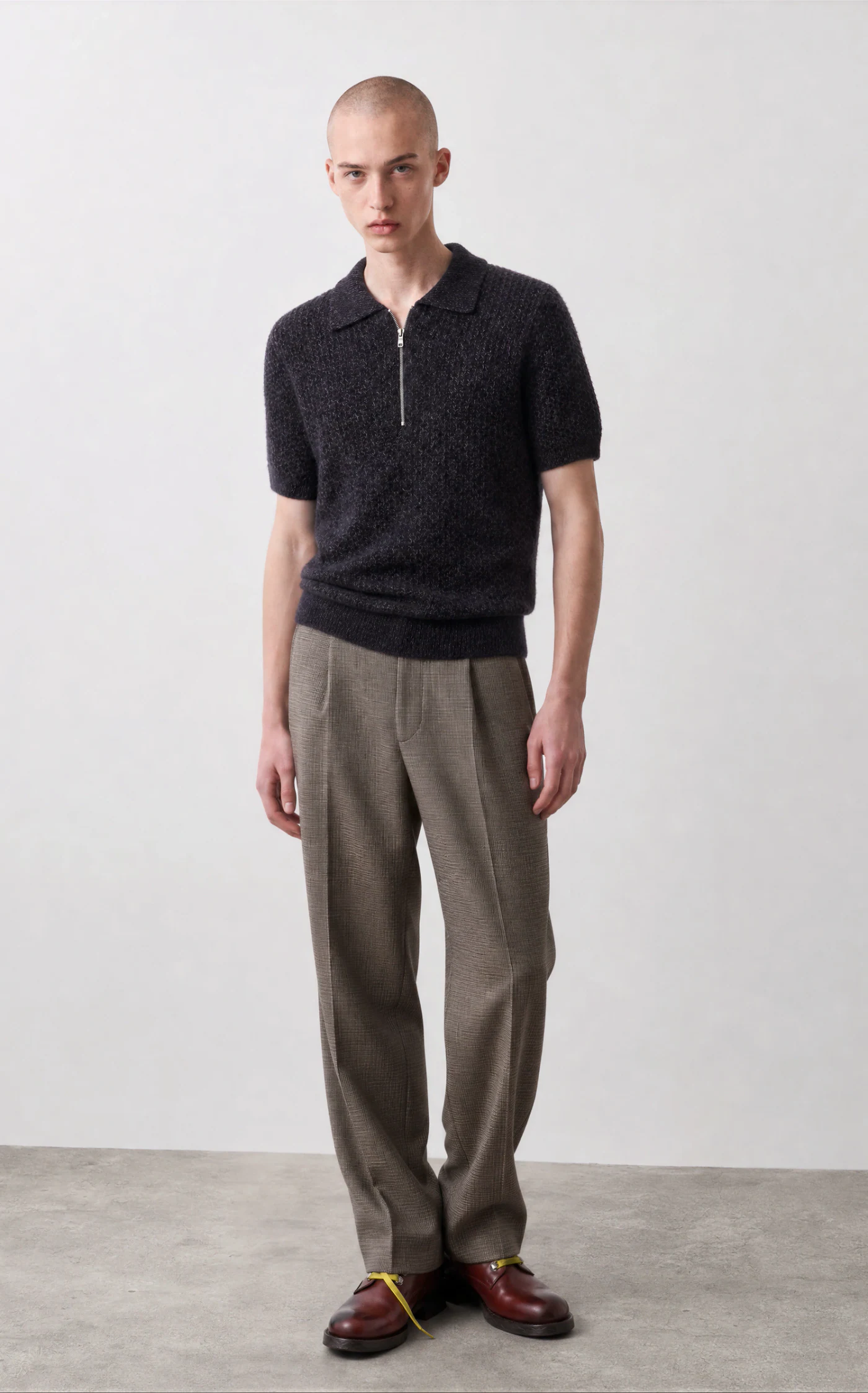 Vestira PDP image — black knit zip polo with pleated trousers, front view